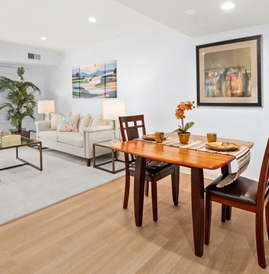 fully furnished, spacious living room and dining area with white rug and walls in senior living apartment